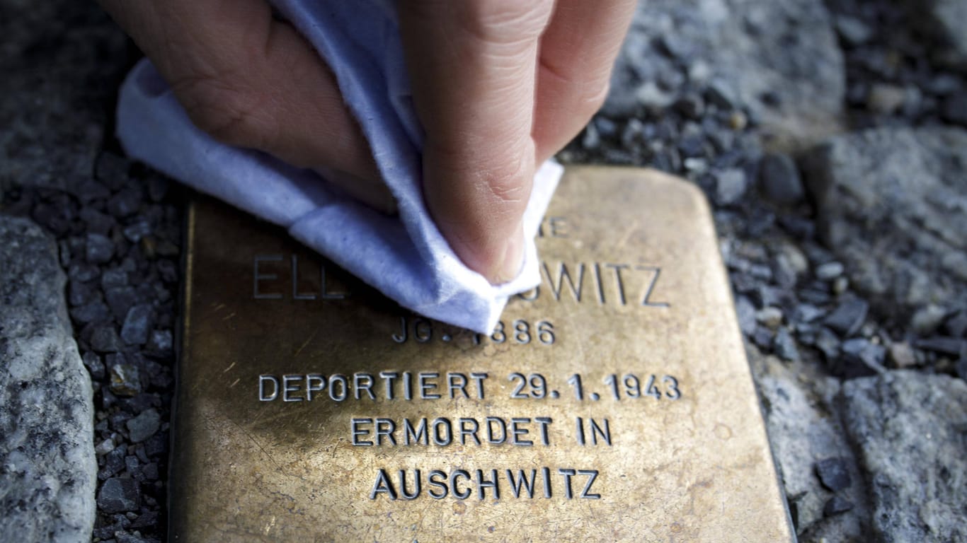 Eine Person putzt einen Stolperstein, der an eine Verfolgte des Nationalsozialismus erinnert (Symbolbild): In Berlin sollen zwei Senioren bei dieser Tätigkeit antisemitisch beleidigt worden sein.