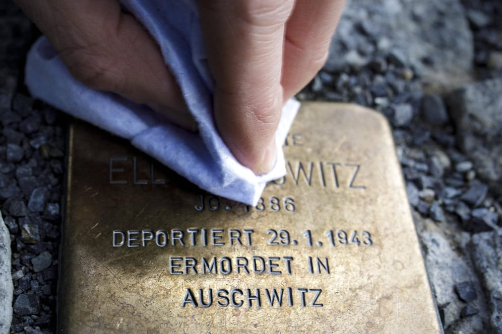 Eine Person putzt einen Stolperstein, der an eine Verfolgte des Nationalsozialismus erinnert (Symbolbild): In Berlin sollen zwei Senioren bei dieser Tätigkeit antisemitisch beleidigt worden sein.