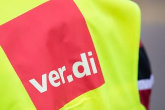 Ein Demonstrant hat eine Warnweste mit der Aufschrift "ver.di" an