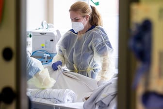 Eine Pflegerin steht am Bett einer Corona-Patientin in Duisburg (Archivbild). Das RKI meldet eine sinkende Inzidenz.