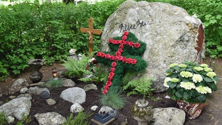 Ein Lothringer Kreuz aus roten Rosen und ein großer Felsbrocken schmücken das Grab des französischen Schauspielers Pierre Brice.