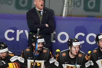 Bundestrainer Toni Söderholm (hinten) ruft Anweisungen an seine Spieler auf dem Eis.