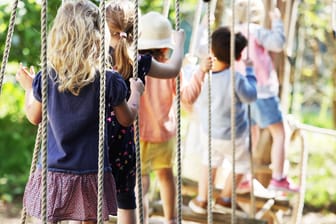 Kinder laufen in einer Kölner Kindertagesstätte über eine Hängebrücke: Kitas in NRW kehren in den Regelbetrieb zurück.
