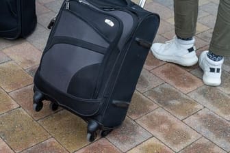 Reisende gehen mit ihren Koffern über die Straße