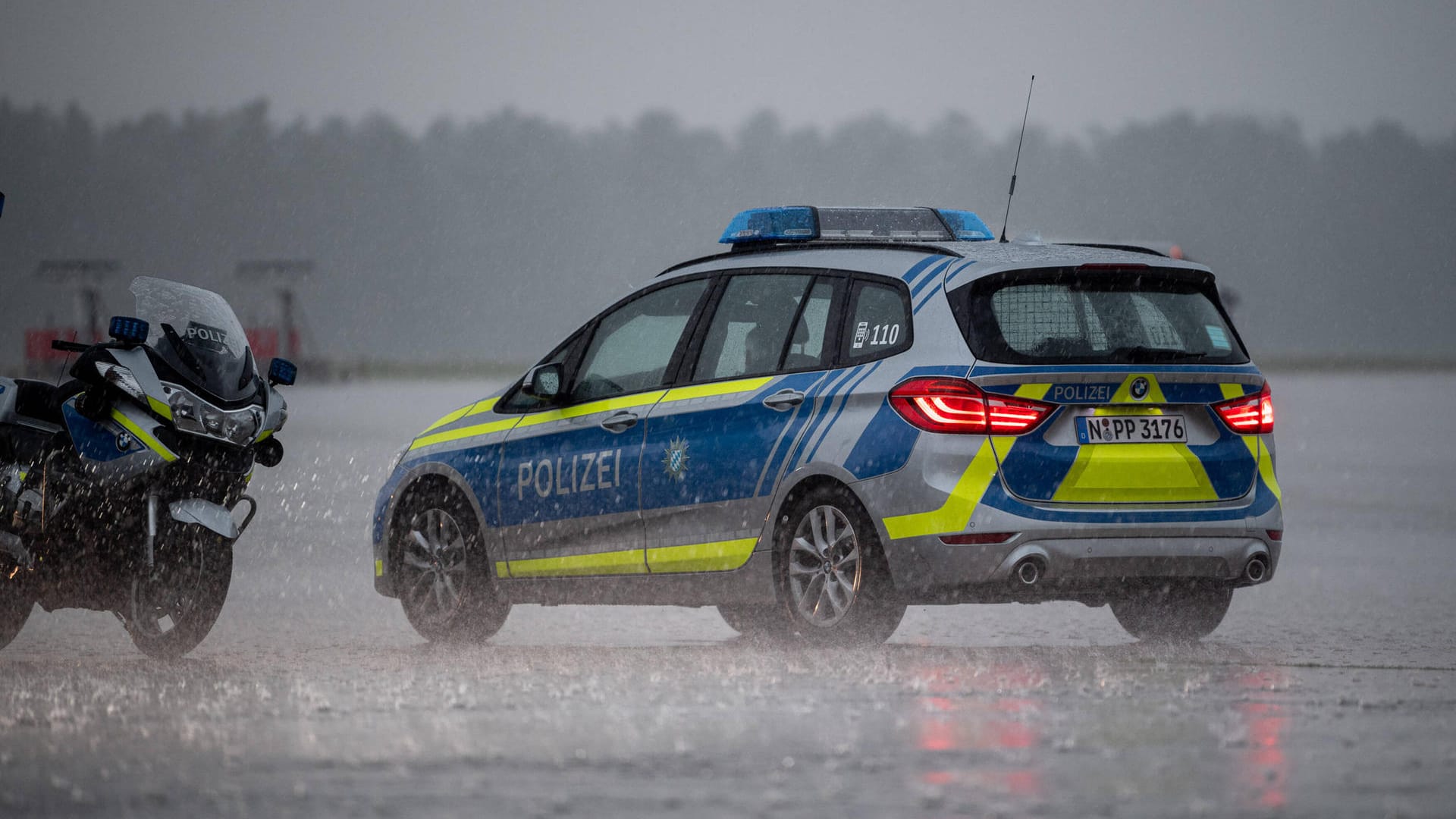 Polizeiautos und Motorräder im Starkregen am Nürnberger Flughafen: Hier ist die Fußballnationalmannschaft am Abend gelandet.