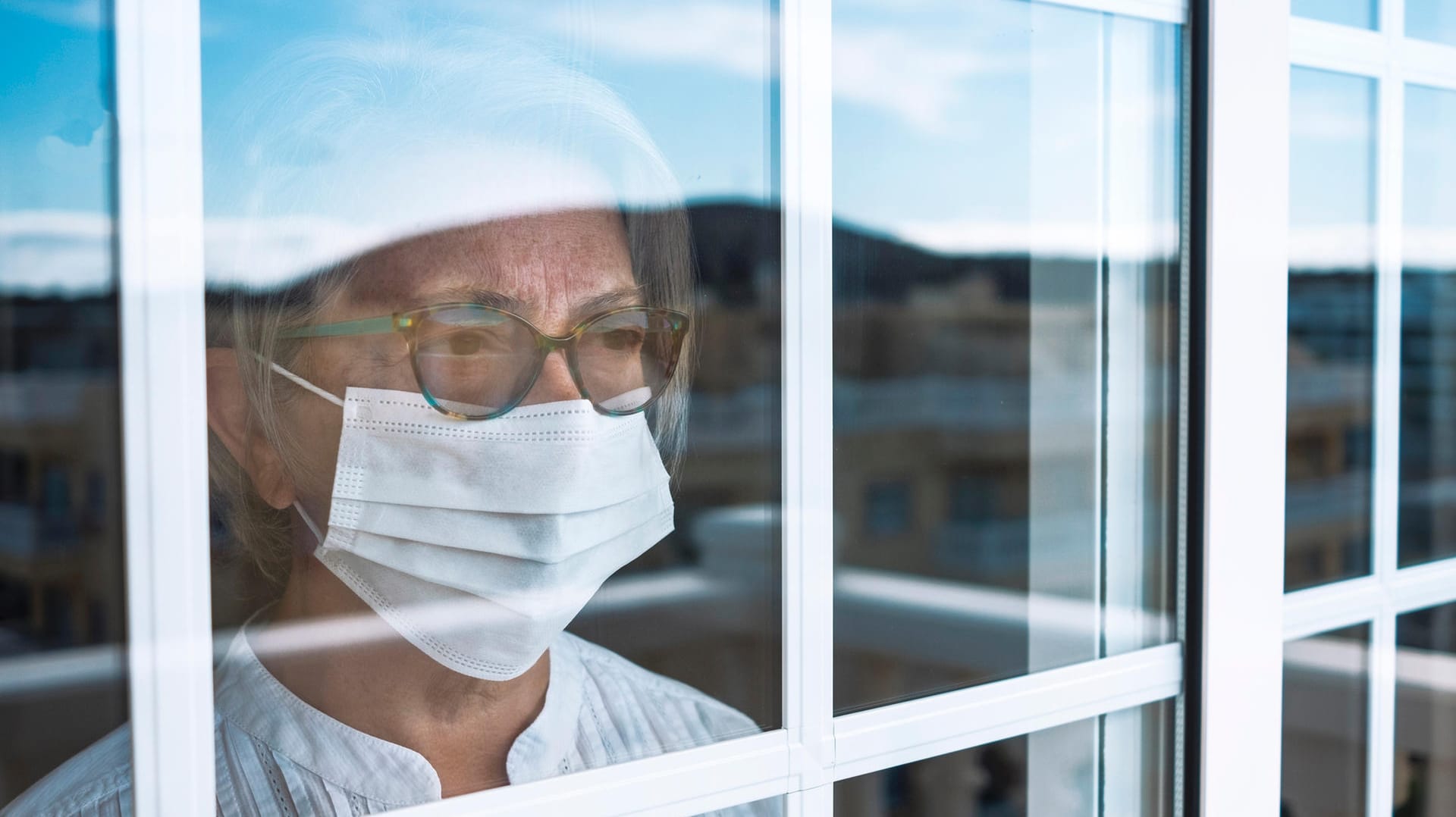 Seniorin blickt aus dem Fenster: Noch immer warten einige Menschen trotz ihrer Priorisierung auf einen Impftermin.