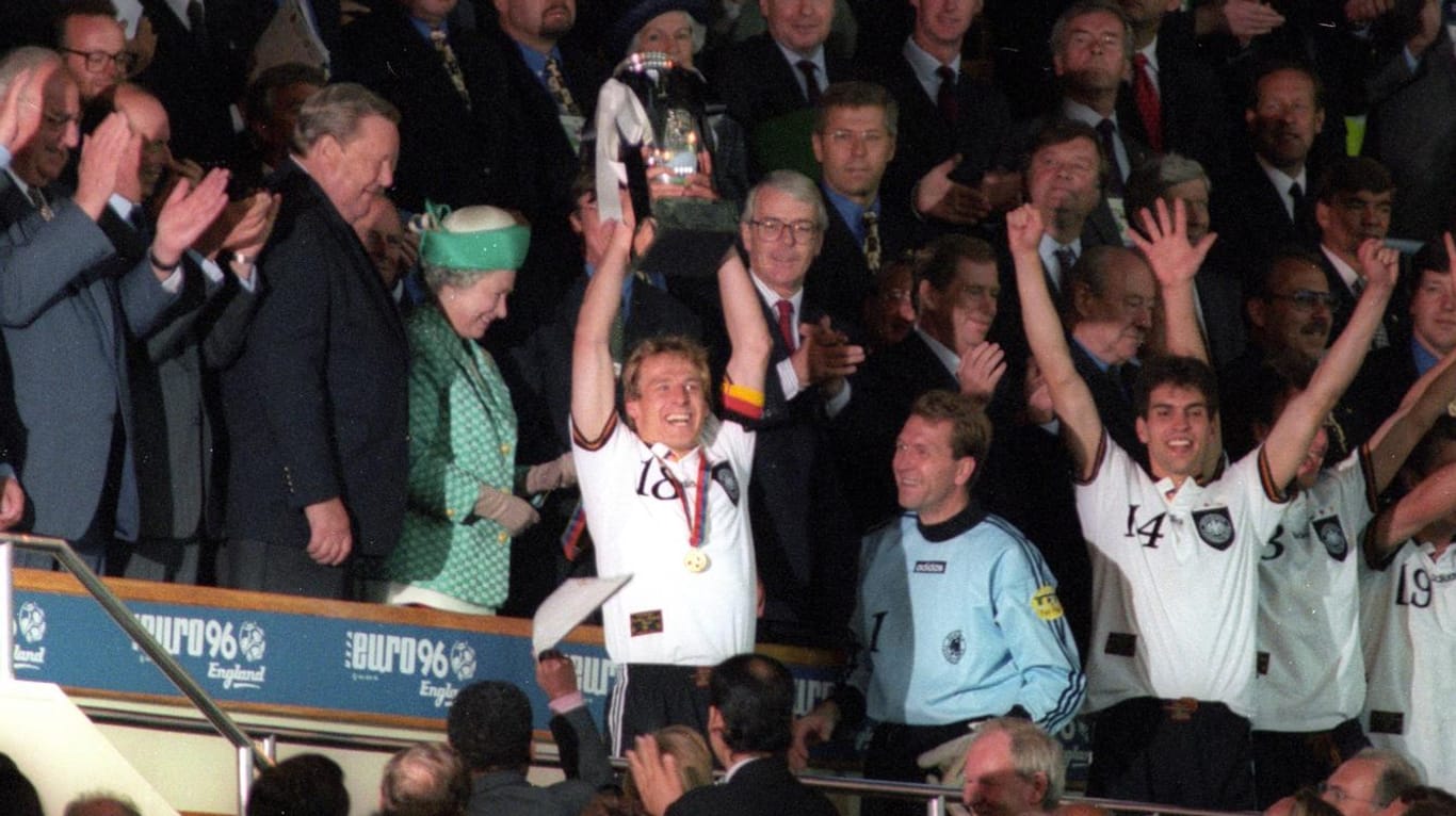 Das letzte Mal Europameister: Kapitän Jürgen Klinsmann (M.) stemmt 1996 den Pokal in die Höhe. Direkt neben ihm steht die Königin von England, Queen Elisabeth.