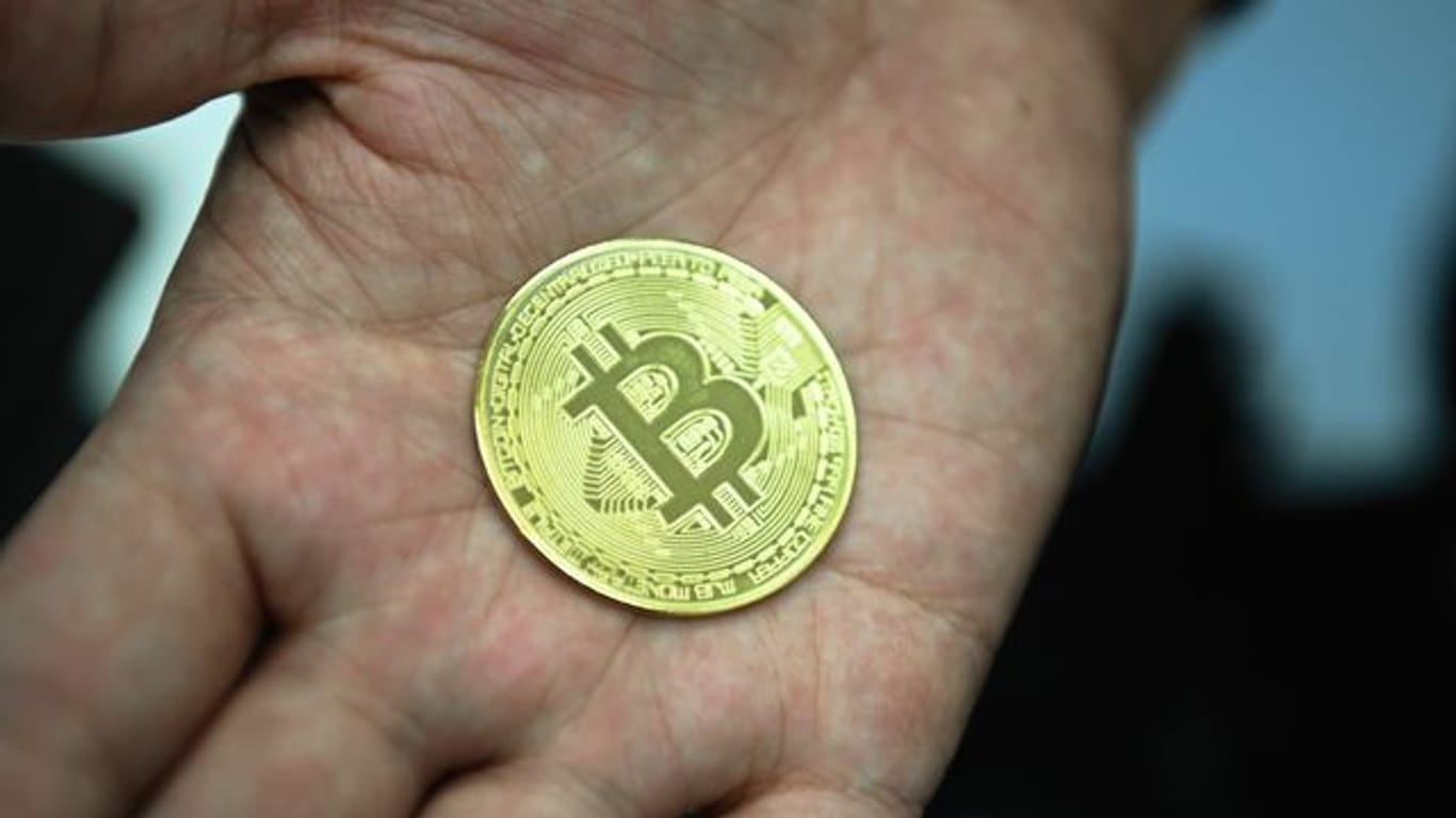 Ein Mann mit eine nachgemachter Münze mit dem Bitcoin-Logo.