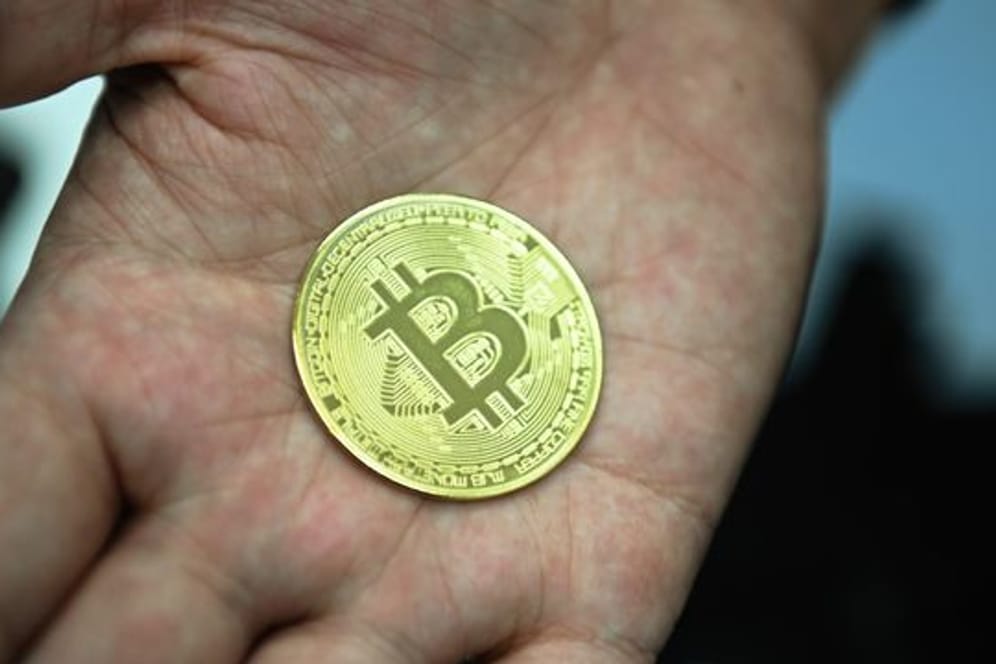 Ein Mann mit eine nachgemachter Münze mit dem Bitcoin-Logo.