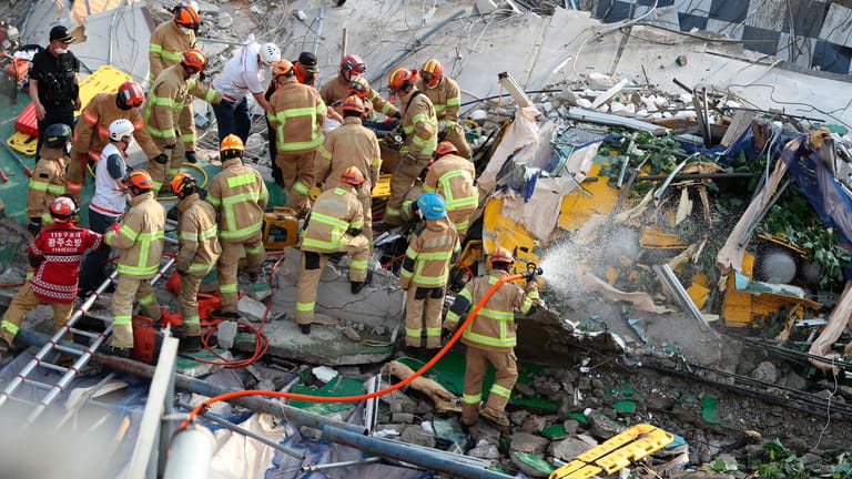 Feuerwehrleute suchen im Wrack des Busses unter den Trümmern nach Überlebenden: Warum das Gebäude unkontrolliert einstürzte, ist bislang nicht bekannt.
