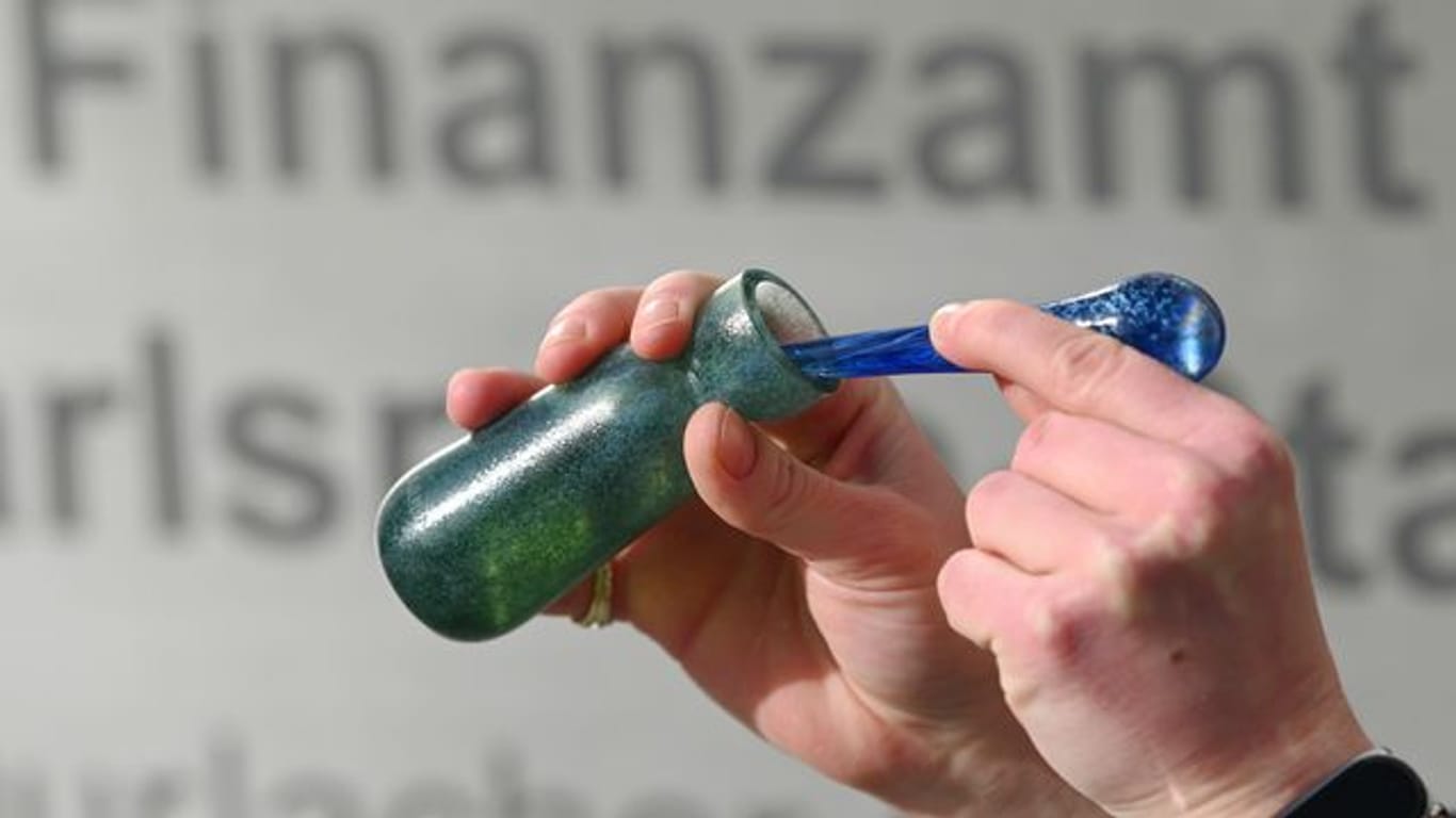 Ein Mann hält vor dem Karlsruher Finanzamt einen Flakon mit Banknoten-Duft, das Parfüm "Aerarium", in der Hand (Archivbild): Das Parfüm wurde im Rahmen von "Kunst am Bau" produziert.