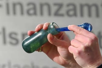 Ein Mann hält vor dem Karlsruher Finanzamt einen Flakon mit Banknoten-Duft, das Parfüm "Aerarium", in der Hand (Archivbild): Das Parfüm wurde im Rahmen von "Kunst am Bau" produziert.