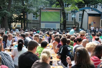 Menschen sehen ein Fußballspiel in einem Biergarten (Archivbild): Dieses Jahr soll es zwar Public Viewing geben – aber mit strengen Regeln.