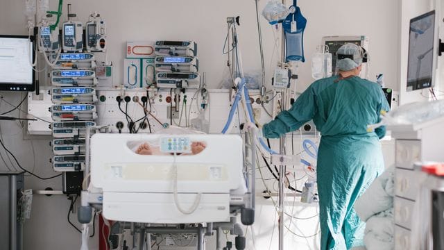 Eine Pflegekraft versorgt einen Patienten auf der Intensivstation