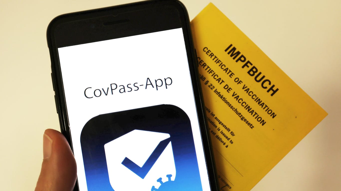 Das Logo der CovPass-App ist neben einem Impfbuch auf einem Smartphone: Der digitale Corona-Impfpass in Deutschland soll an diesem Donnerstag starten.
