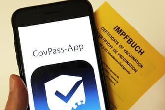 Das Logo der CovPass-App ist neben einem Impfbuch auf einem Smartphone: Der digitale Corona-Impfpass in Deutschland soll an diesem Donnerstag starten.