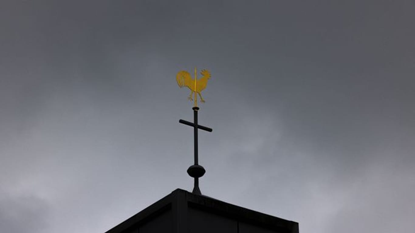 Blick auf ein Kreuz und einen Wetterhahn auf einer Kirche