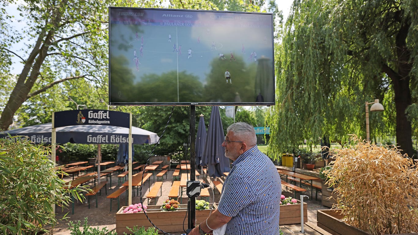 Josef Rayes, Betreiber des Biergartens am Aachener Weiher, stellt einen Fernsehbildschirm auf: Auf große Public Viewing Veranstaltungen müssen die Fußballfans dieses Jahr verzichten. Und auch in den Biergärten und Bars gelten Abstandsregeln.