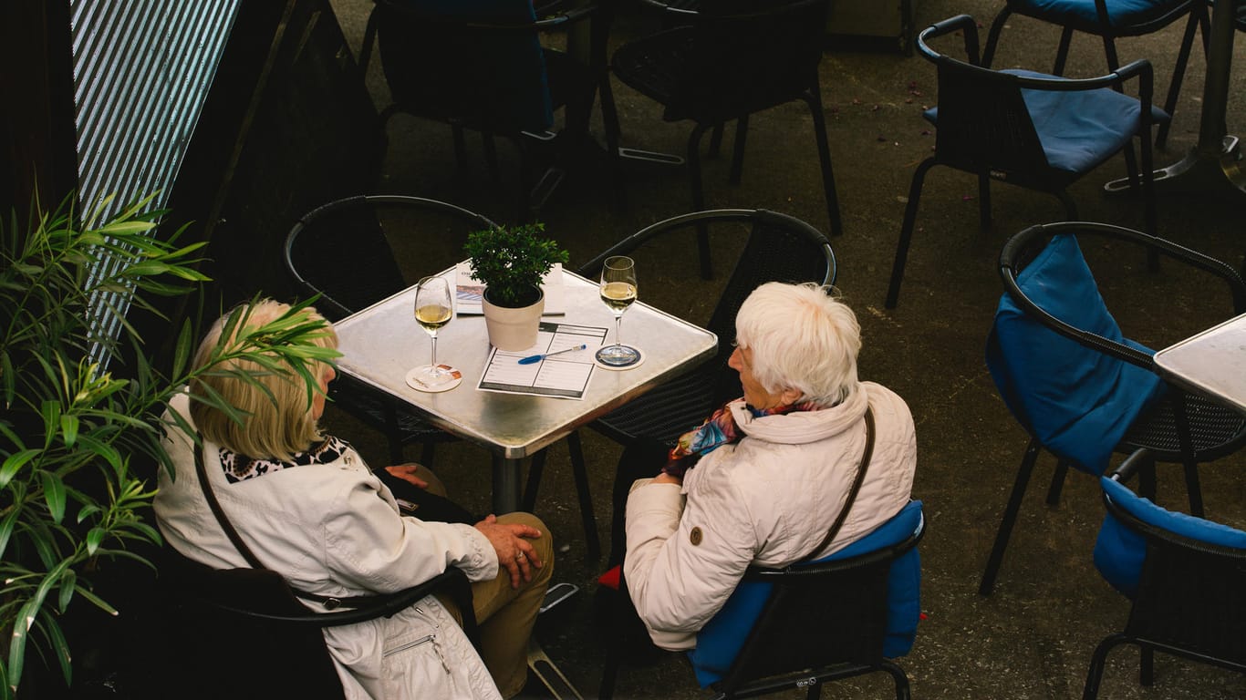 Zwei Personen sitzen im Außenbereich eines Restaurants in Düsseldorf: Ab sofort ist auch der Innenbereich wieder ohne Test zugängig.