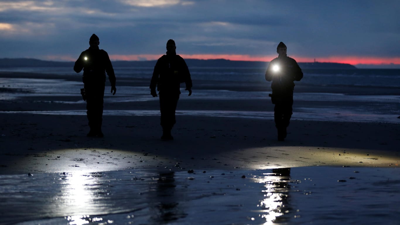 Französische Polizisten kontrollieren den Strand nahe Calais: Oft verstecken sich die Menschen in den Dünen, um dann schnell mit Schlauchbooten auf das Meer zu gelangen.