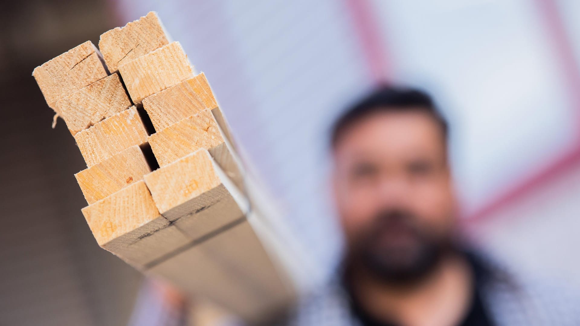 Ein Dachdecker hält an seinem Dachlatten aus Holz: Wegen des Materialmangels geht es auf einigen Baustellen derzeit nur langsam voran.