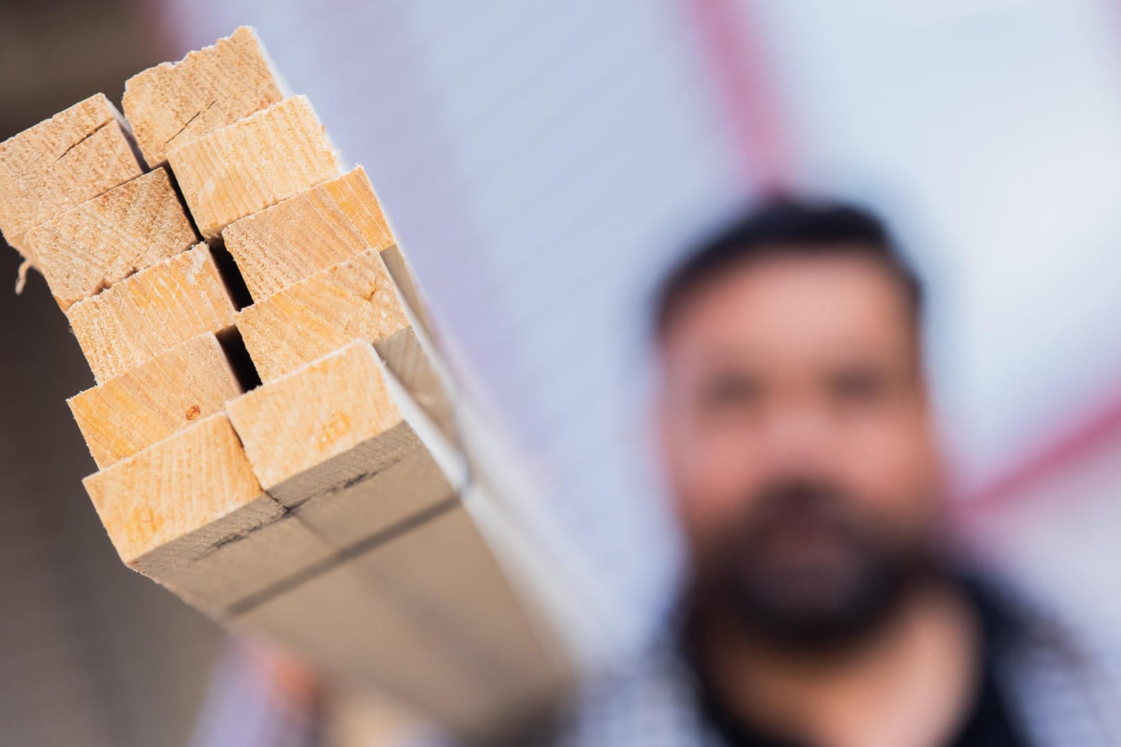 Ein Dachdecker hält an seinem Dachlatten aus Holz: Wegen des Materialmangels geht es auf einigen Baustellen derzeit nur langsam voran.