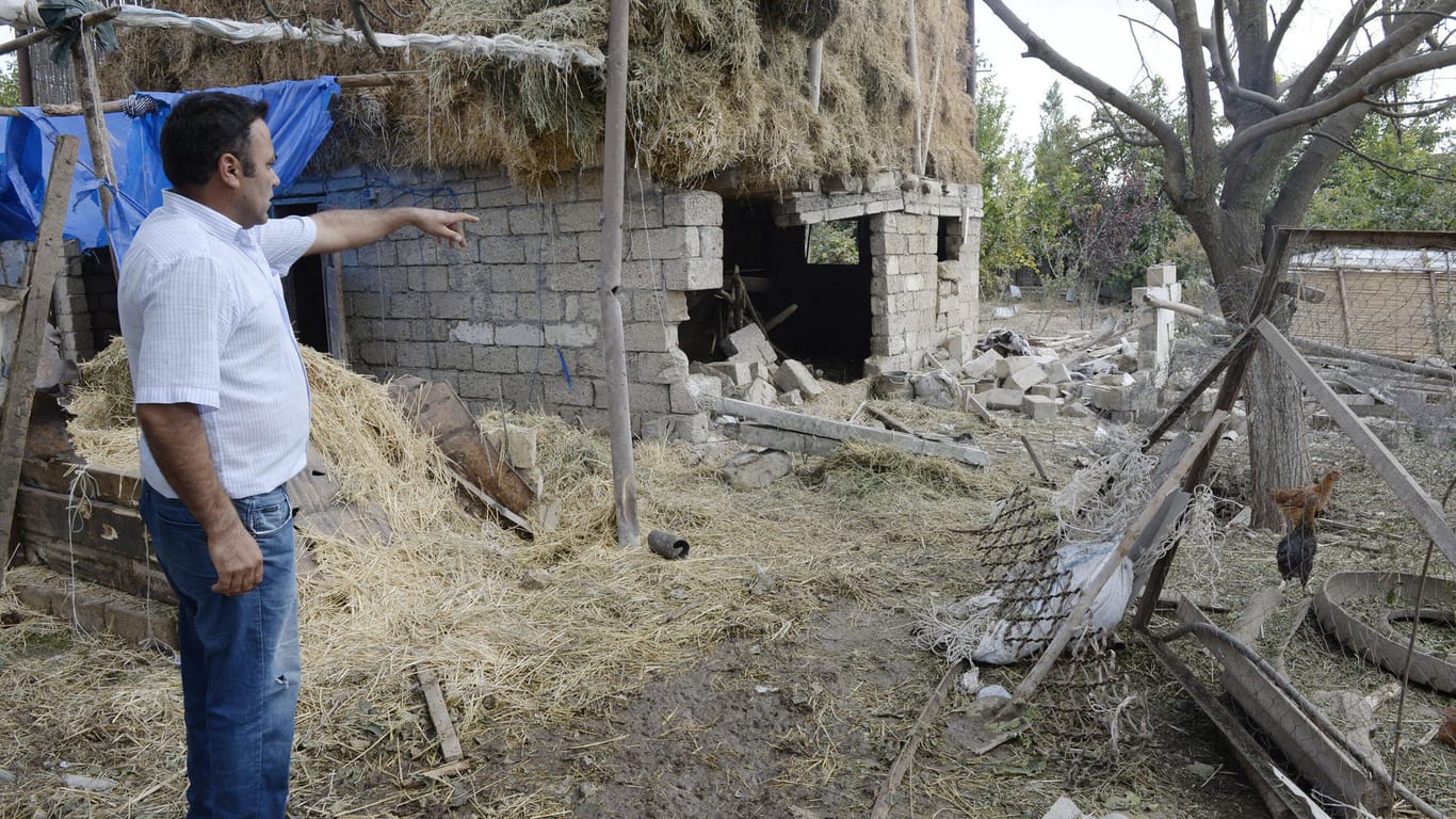 Ein Mann zeigt auf ein zerstörtes Haus in Berg-Karabach (Archivbild). In der Region wurden auch Tausende Minen verlegt.