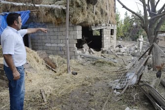 Ein Mann zeigt auf ein zerstörtes Haus in Berg-Karabach (Archivbild). In der Region wurden auch Tausende Minen verlegt.