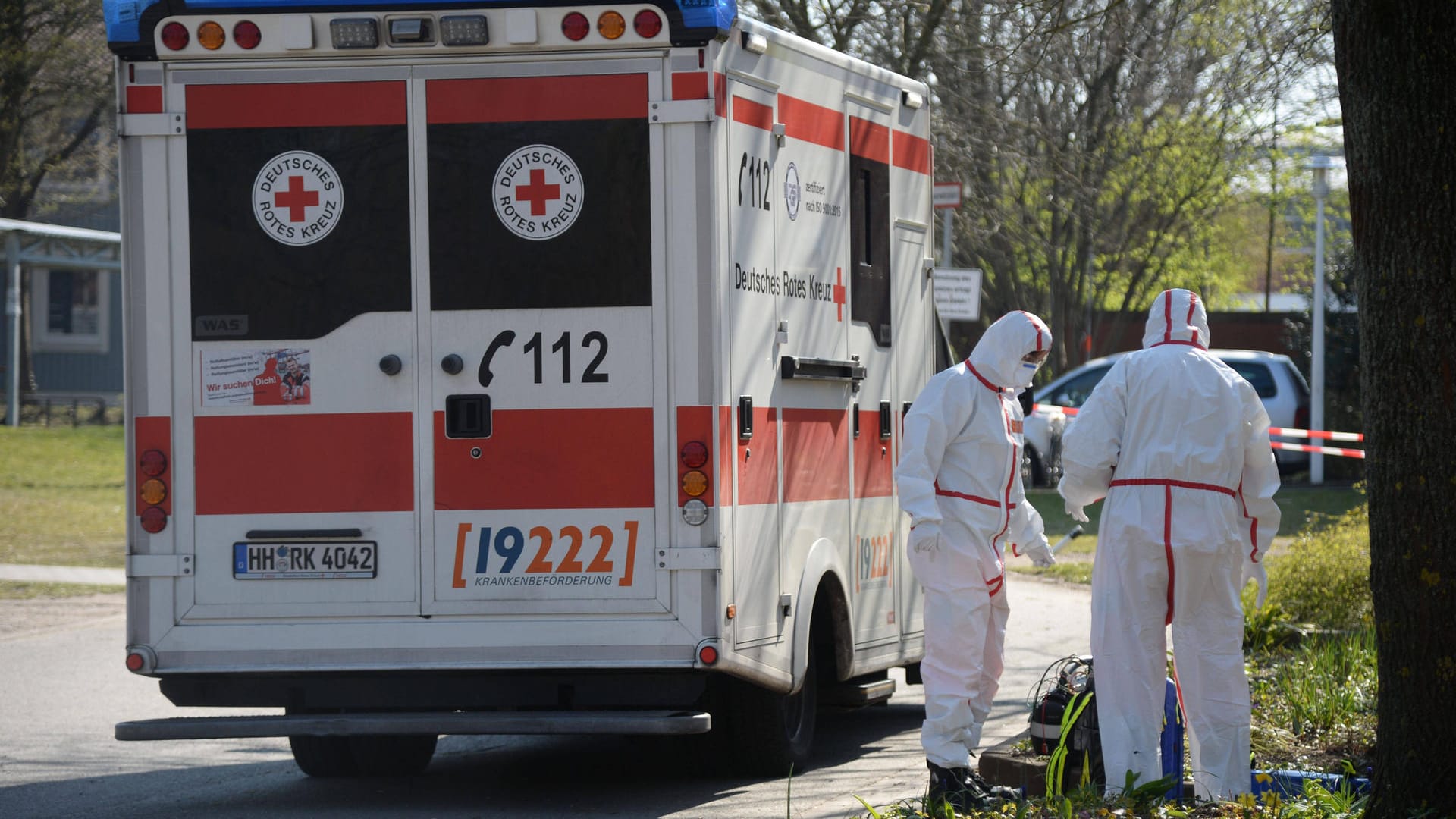 Ein Rettungswagen und Sanitäter in Schutzanzügen bei einem Einsatz in Hamburg (Archivbild). Noch immer sterben viele Menschen am Coronavirus. Ein Rettungswagen und Sanitäter in Schutzanzügen bei einem Einsatz in Hamburg (Archivbild). Noch immer sterben viele Menschen am Coronavirus.