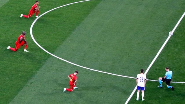 Belgische Spieler und Schiedsrichter Antonio Mateu Lahoz knien vor dem Spiel gegen Russland.