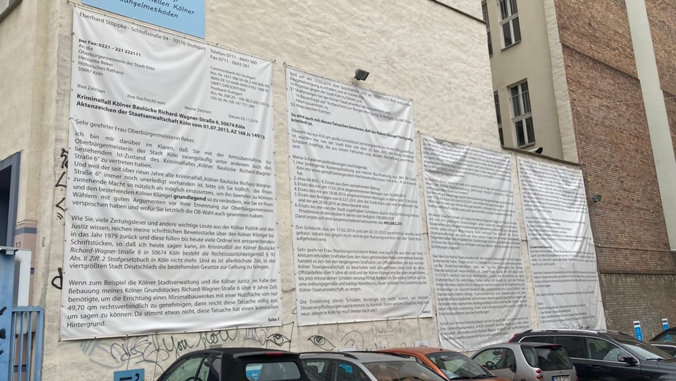 Großformatige Briefe hängen ausgedruckt an der Fassade des Nachbarhauses: Auch hier ist vom "Kriminalfall Kölner Baulücke" die Rede.