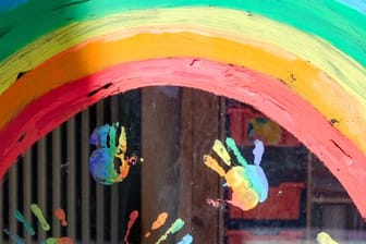 Kinderhände und ein Regenbogen sind an einer Kita zu sehen. (Symbolbild)
