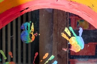 Kinderhände und ein Regenbogen sind an einer Kita zu sehen. (Symbolbild)