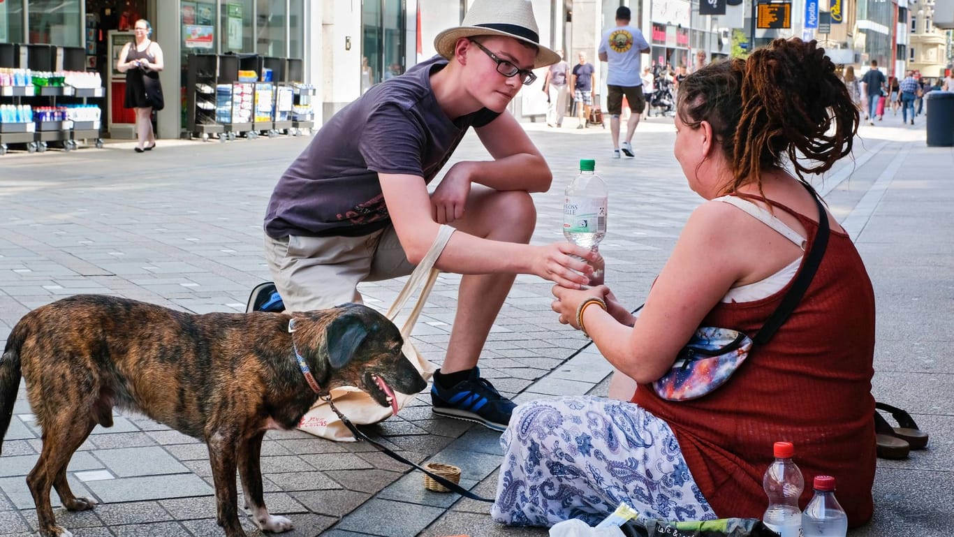 Ein Helfer gibt einer Obdachlosen Wasser (Symbolbild): Angesichts der Hitze hat die Berliner Stadtmission dazu aufgerufen, Obdachlosen zu helfen.