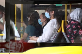 Menschen mit Maske im Bus: Wird bald die Maskenpflicht draußen enden?