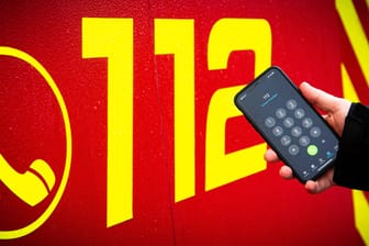 Die Notrufnummer "112" steht auf einem Einsatzfahrzeug und im Eingabefeld eines Smartphones: Das Handy ist der Anrufer los.