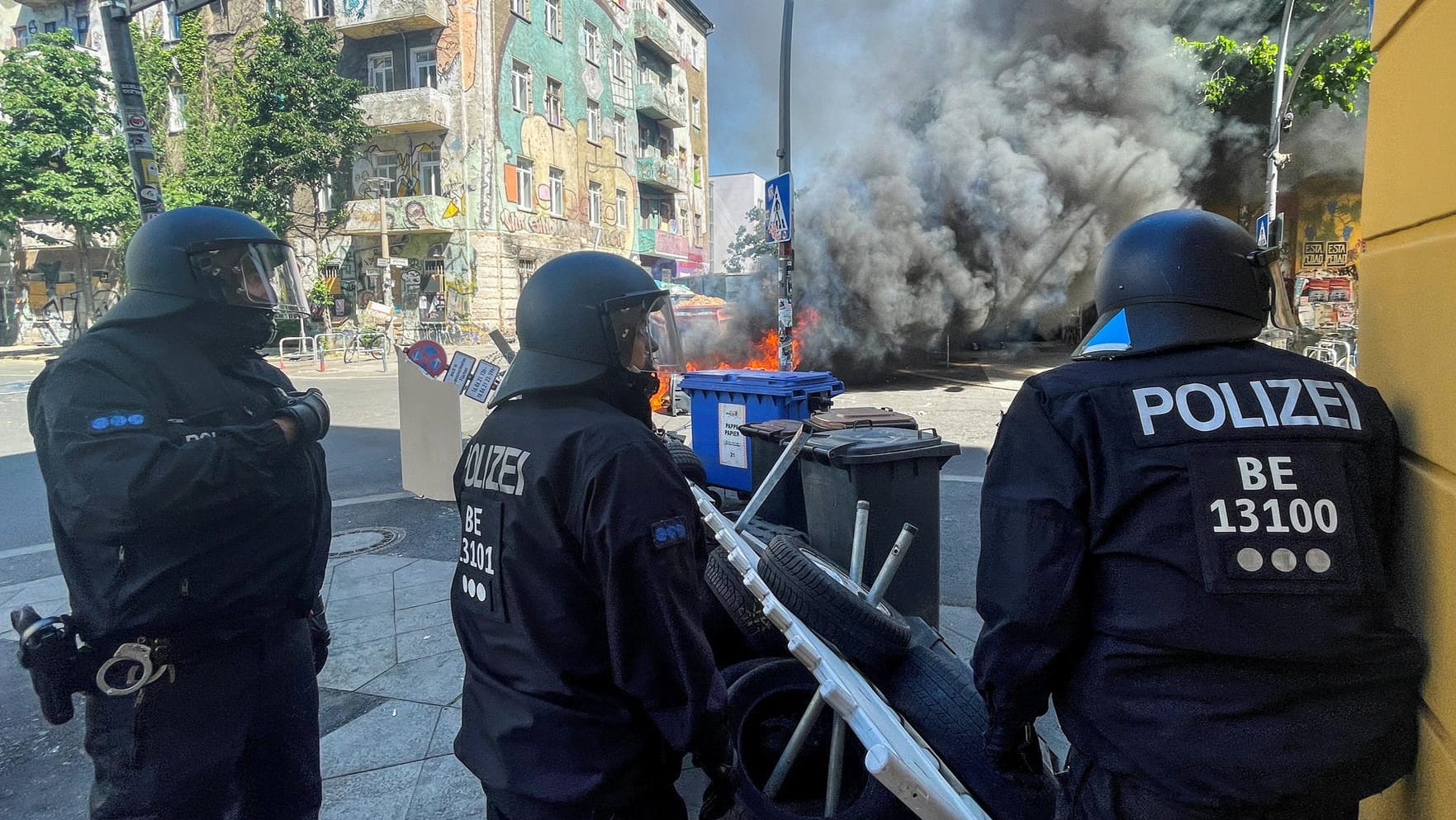 Police officers stand near burning barricades at Rigaer Street in Berlin