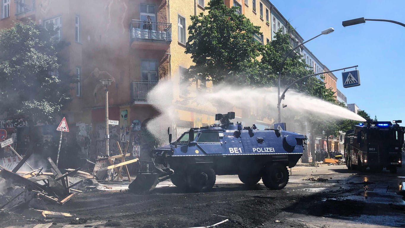 Ein Räumpanzer der Polizei schiebt in der Rigaer Straße in Berlin-Friedrichshain eine Barrikade beiseite, dahinter fährt ein Wasserwerfer: Mit den Wasserwerfern wurden auch Teile der Barrikaden gelöscht.