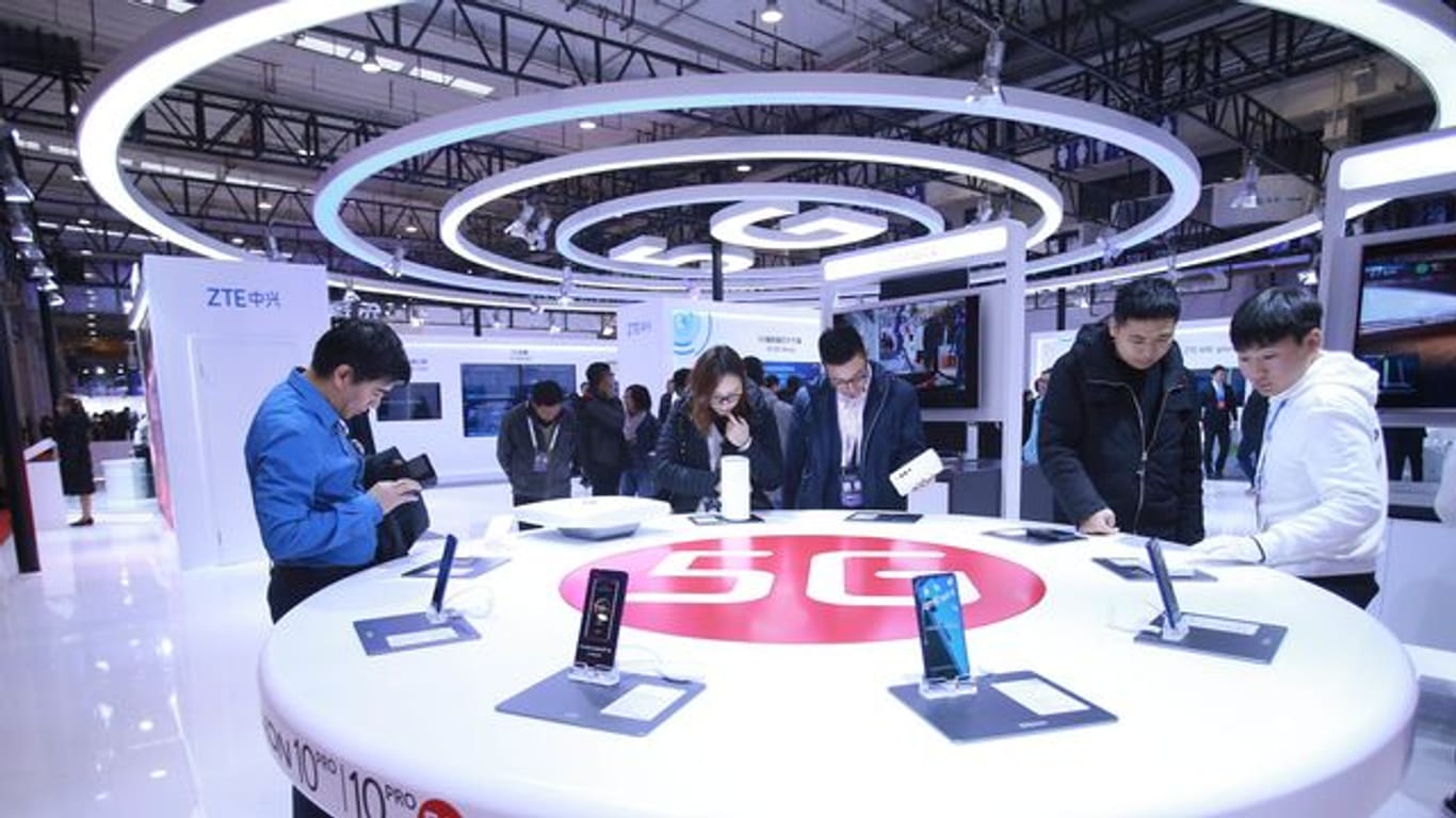 Besucher schauen neue Smartphones mit 5G-Technologie an.
