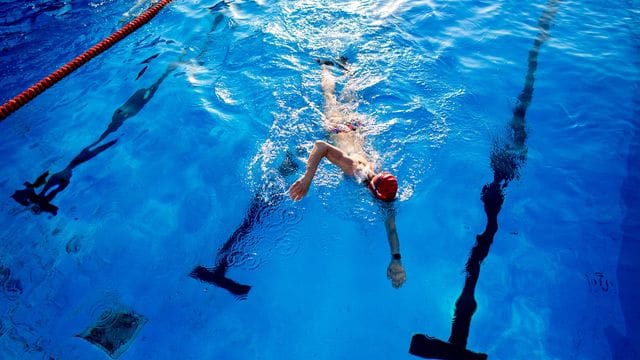 Eine Frau schwimmt am frühen Morgen durch ein Becken