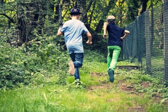 Zwei Jungs rennen mit Softairwaffen weg (Symbolbild): Die Waffe des Jungen sah täuschend echt aus.