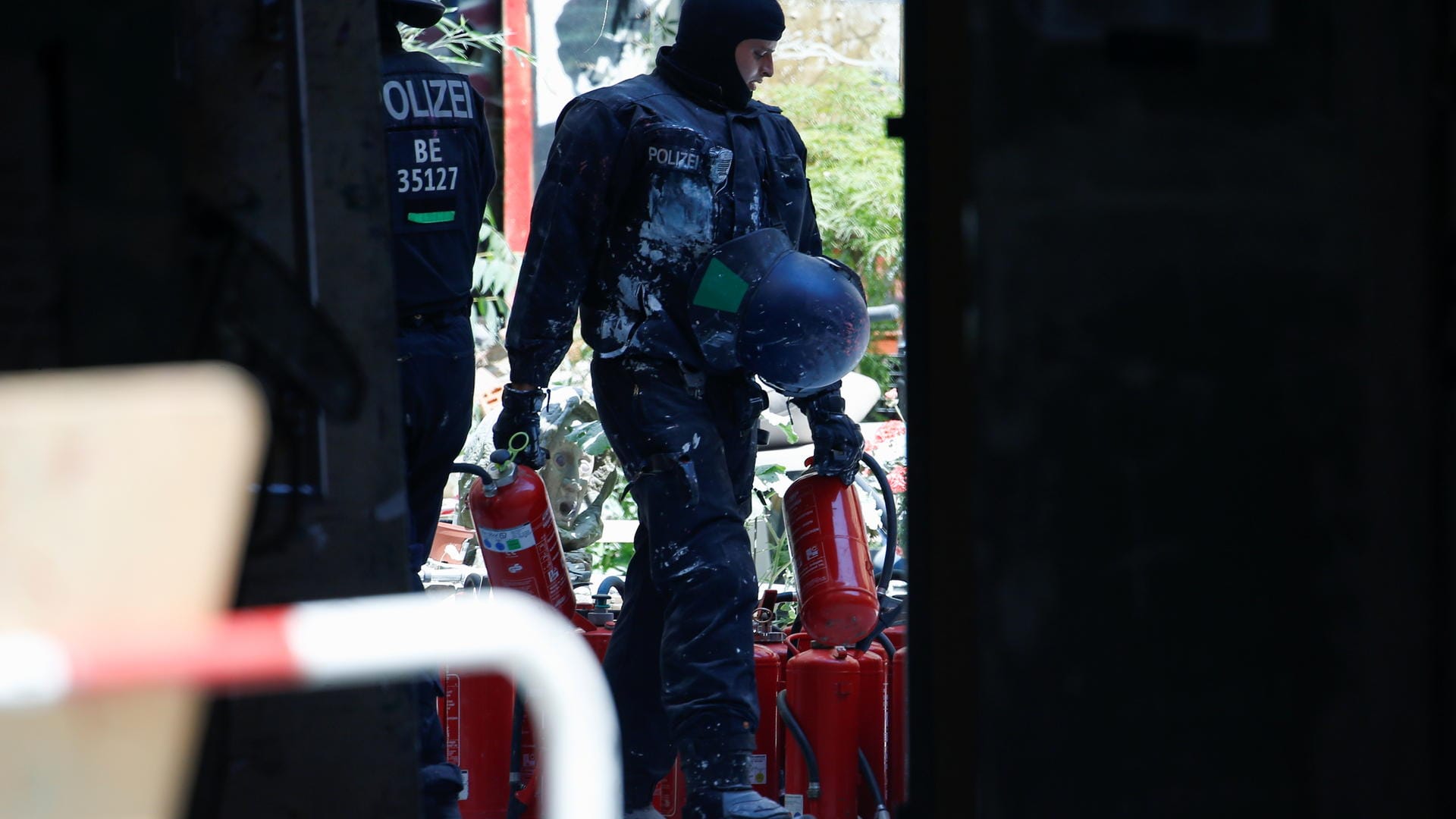 Polizist mit Feuerlöschern: Die Einsatzkräfte wurden damit besprüht.