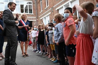 Emmanuel Macron spricht mit Schülerinnen und Schülern einer Grundschule zum Abschluss eines eintägigen Besuchs in Nordfrankreich.