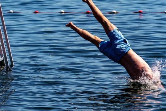 Ein junger Mann springt in die Kieler Förde