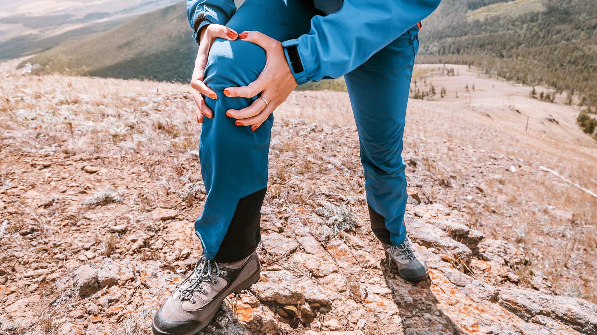 Eine Frau hält mit den Händen ihr rechtes Knie. Wandern ist ideal, um Gelenkverschleiß vorzubeugen. Vorausgesetzt, Sie beachten einige wichtige Regeln.