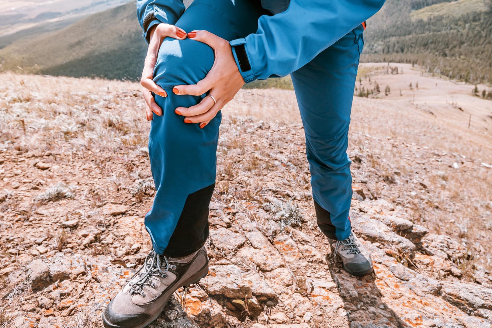 Eine Frau hält mit den Händen ihr rechtes Knie. Wandern ist ideal, um Gelenkverschleiß vorzubeugen. Vorausgesetzt, Sie beachten einige wichtige Regeln.