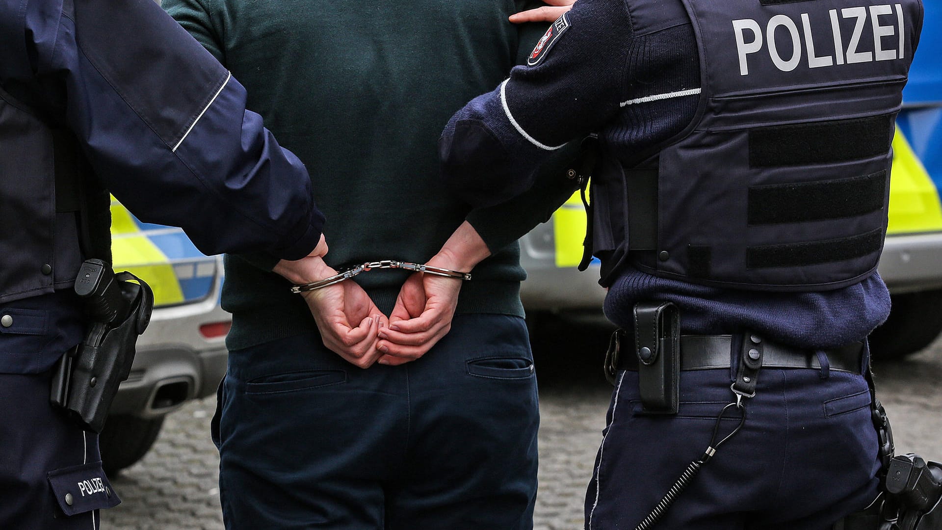 Zwei Polizisten mit einem Mann in Handschellen (Symbolbild): In Leverkusen hat die Polizei einen per Haftbefehl Gesuchten gestellt. Zwei Polizisten mit einem Mann in Handschellen (Symbolbild): In Leverkusen hat die Polizei einen per Haftbefehl Gesuchten gestellt.