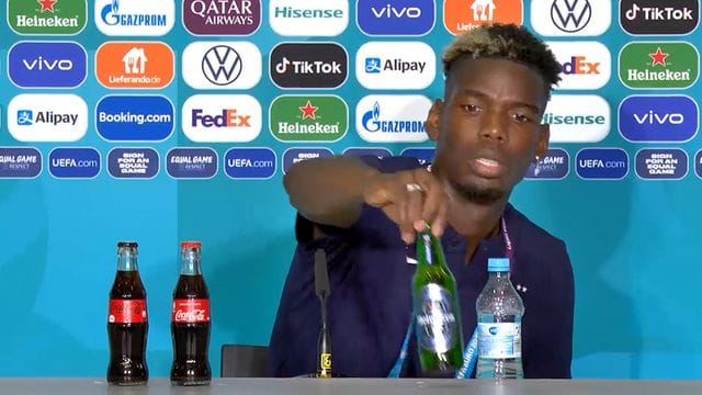 Paul Pogba entfernt eine Heineken-Flasche vom Tisch der Pressekonferenz.