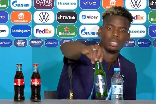 Paul Pogba entfernt eine Heineken-Flasche vom Tisch der Pressekonferenz.