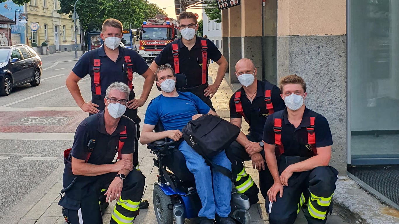 Helmut sitzt in seinem Rollstuhl – neben ihm stehen und knien Feuerwehrmänner: Die Einsatzkräfte haben ihn aus einer misslichen Lage befreit.
